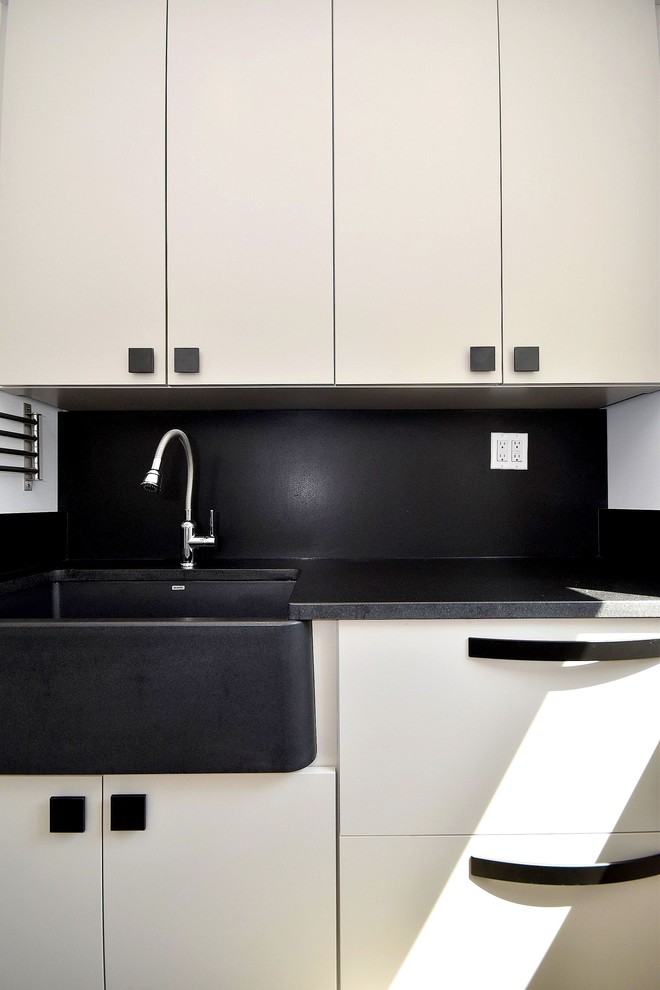 Idéer för funkis parallella svart tvättstugor enbart för tvätt, med en rustik diskho, släta luckor, vita skåp och en tvättmaskin och torktumlare bredvid varandra