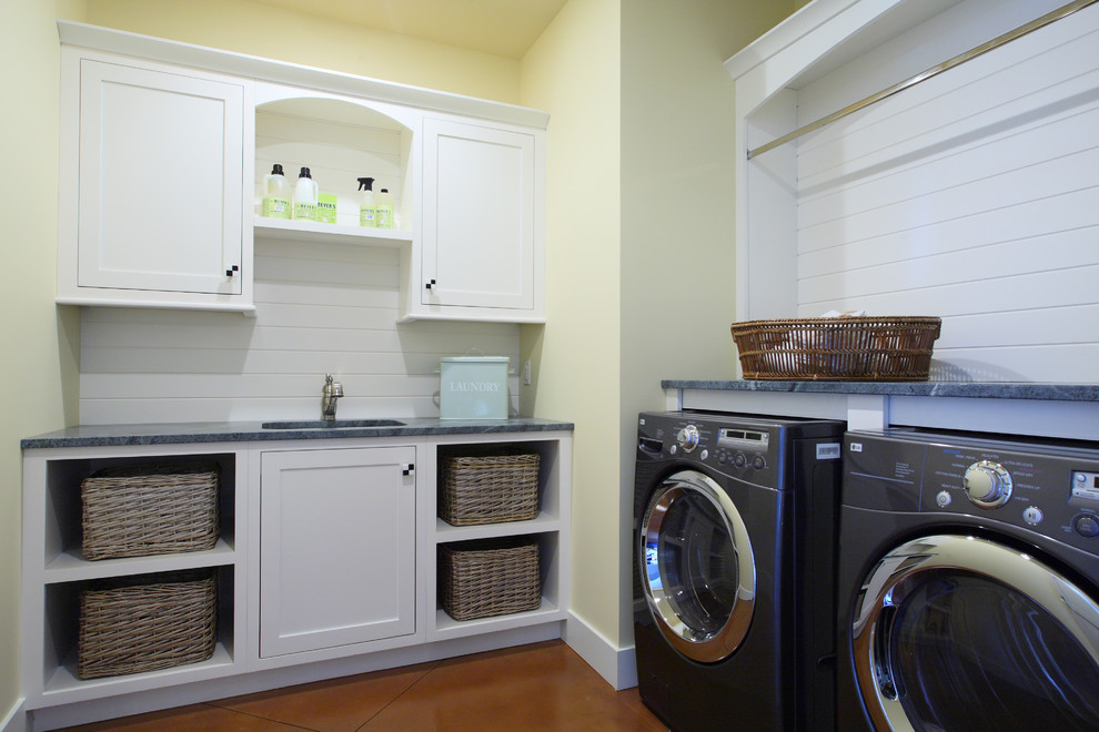 Ejemplo de lavadero en L tradicional grande con paredes amarillas, fregadero bajoencimera, puertas de armario blancas, encimera de granito, lavadora y secadora juntas y armarios estilo shaker