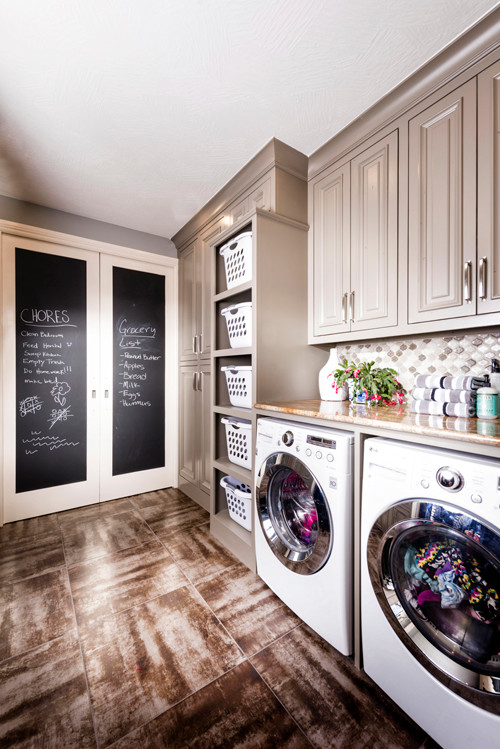 Bild på en stor vintage parallell tvättstuga enbart för tvätt, med grå skåp, granitbänkskiva, grå väggar, klinkergolv i porslin, en tvättmaskin och torktumlare bredvid varandra och luckor med upphöjd panel