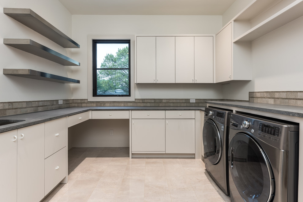 Idéer för mellanstora funkis u-formade grått tvättstugor enbart för tvätt, med en undermonterad diskho, släta luckor, vita skåp, bänkskiva i betong, vita väggar, betonggolv, en tvättmaskin och torktumlare bredvid varandra och vitt golv