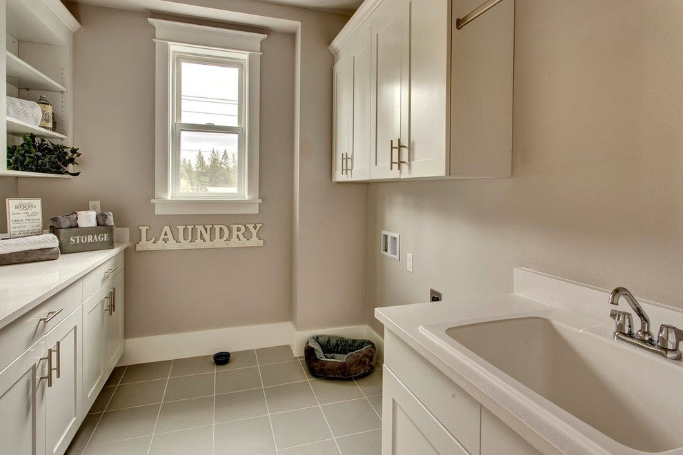 Example of a large galley ceramic tile dedicated laundry room design in Seattle with a drop-in sink, gray walls, white cabinets, flat-panel cabinets and a side-by-side washer/dryer