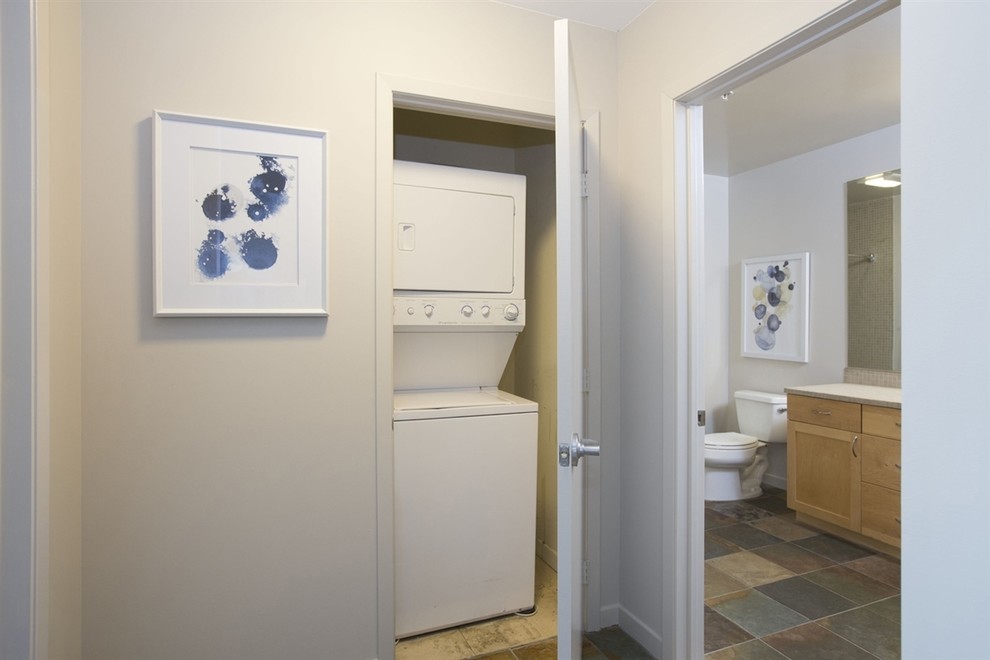 Immagine di un piccolo ripostiglio-lavanderia eclettico con pareti grigie e lavatrice e asciugatrice a colonna