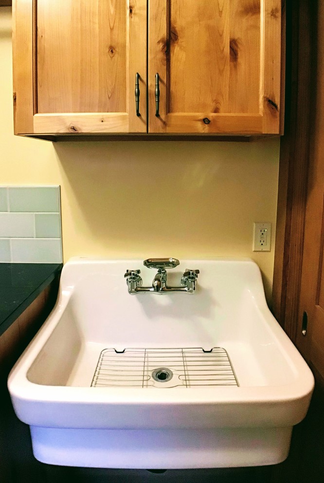Photo of a small classic galley separated utility room in Portland with a belfast sink, beaded cabinets, medium wood cabinets, engineered stone countertops, yellow walls, slate flooring, a side by side washer and dryer, grey floors and black worktops.