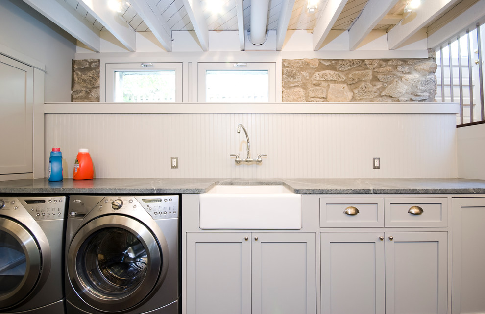 Diseño de lavadero clásico con fregadero sobremueble y puertas de armario grises