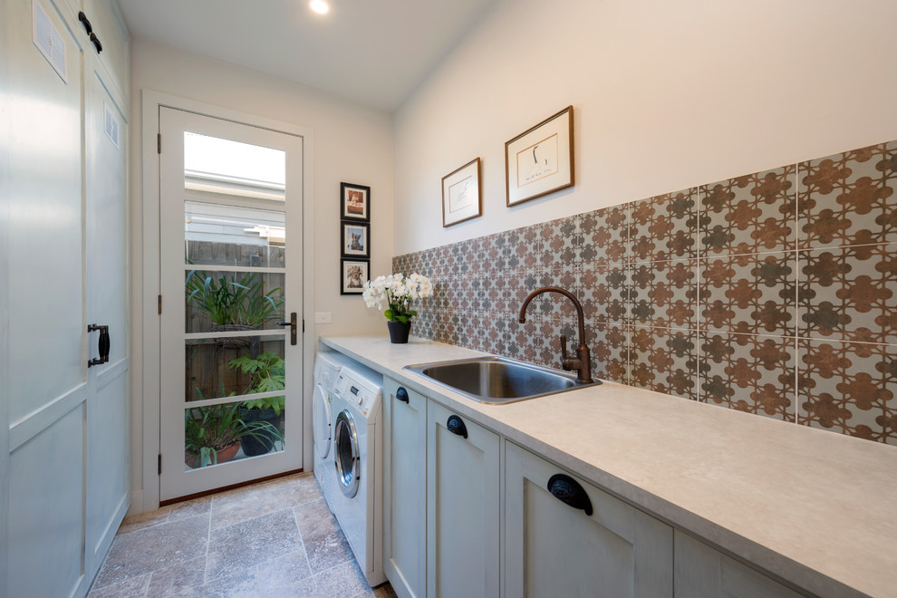 Zweizeilige, Kleine Mediterrane Waschküche mit Einbauwaschbecken, Schrankfronten im Shaker-Stil, weißer Wandfarbe, Travertin, Waschmaschine und Trockner nebeneinander, Laminat-Arbeitsplatte und weißen Schränken in Melbourne