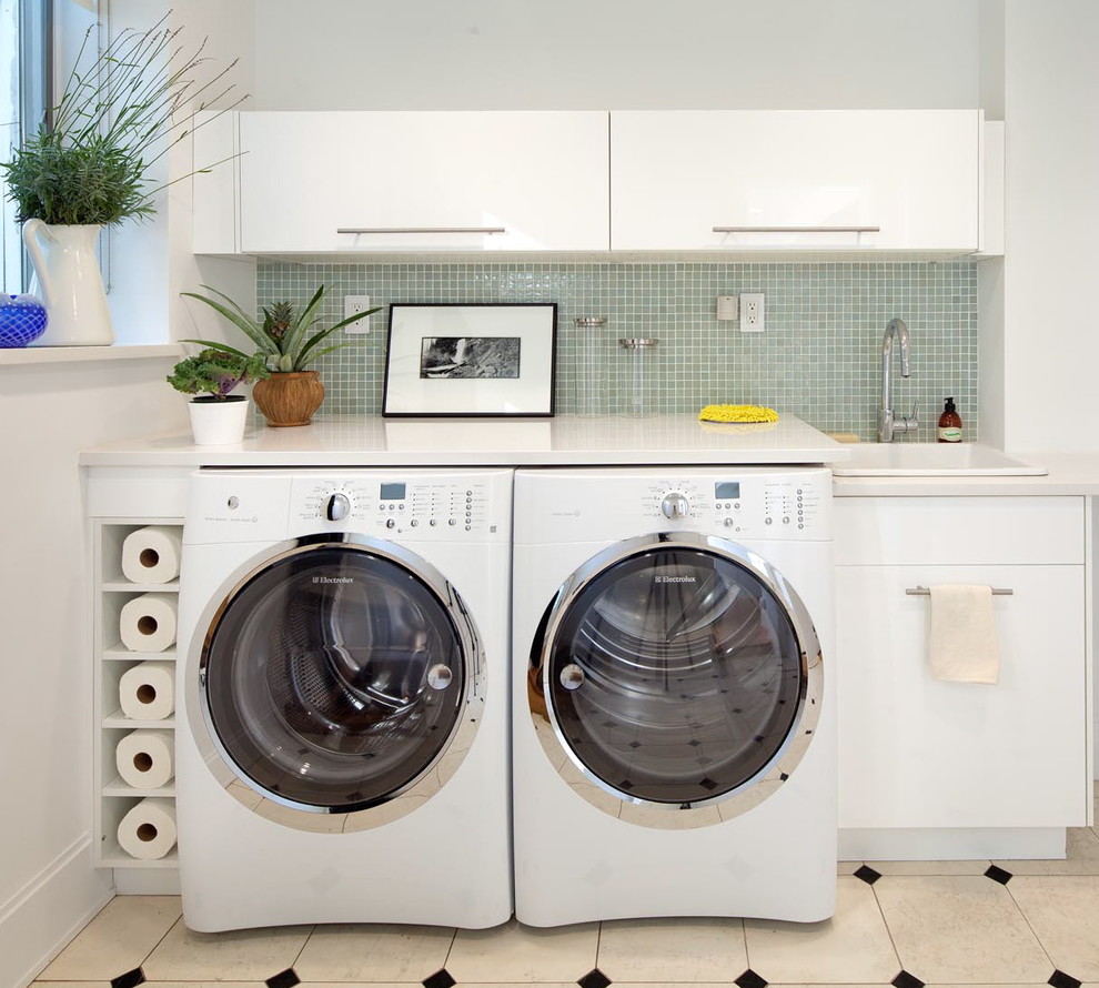 Moderner Hauswirtschaftsraum mit Einbauwaschbecken, flächenbündigen Schrankfronten, weißen Schränken, Waschmaschine und Trockner nebeneinander und weißer Arbeitsplatte in New York