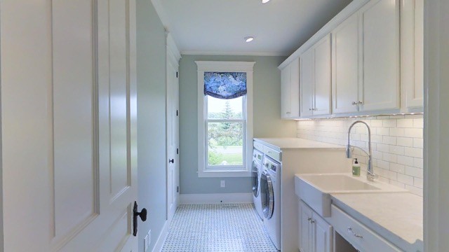 Inredning av en klassisk parallell tvättstuga enbart för tvätt, med en rustik diskho, vita skåp, marmorbänkskiva, gröna väggar, marmorgolv och en tvättmaskin och torktumlare bredvid varandra