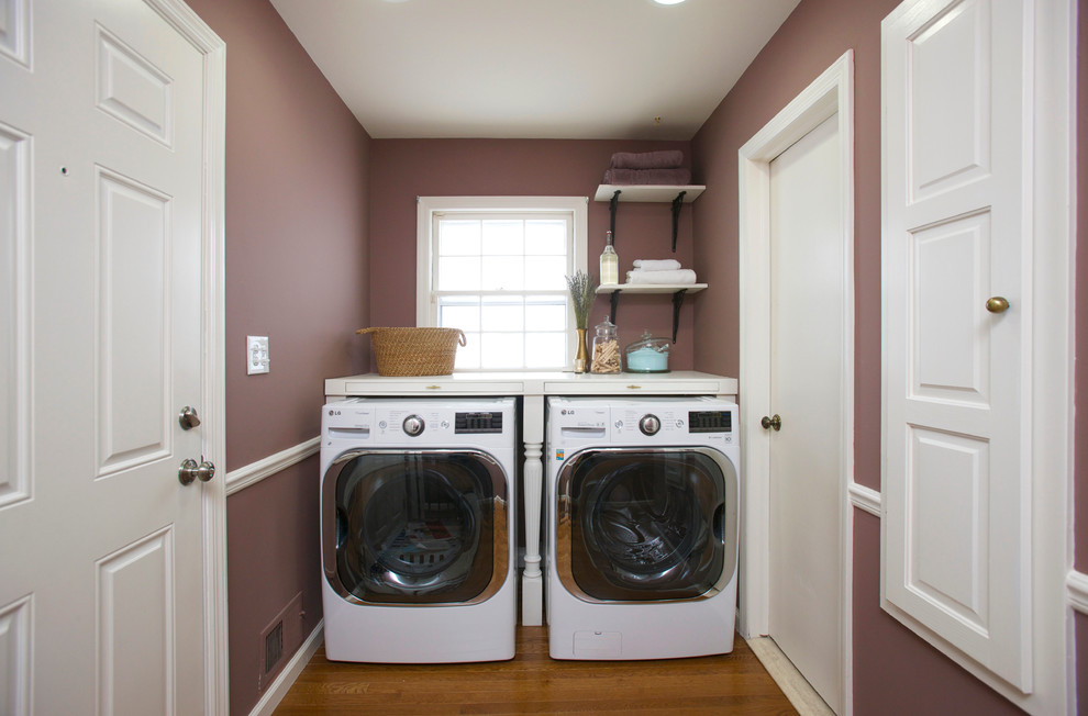 Modelo de cuarto de lavado lineal clásico renovado pequeño con encimera de madera, paredes púrpuras, suelo de madera en tonos medios y lavadora y secadora juntas