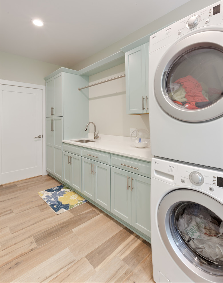 Foto på en stor funkis vita linjär tvättstuga enbart för tvätt, med en undermonterad diskho, skåp i shakerstil, bänkskiva i kvarts, klinkergolv i porslin, en tvättpelare, blå skåp, vita väggar och beiget golv