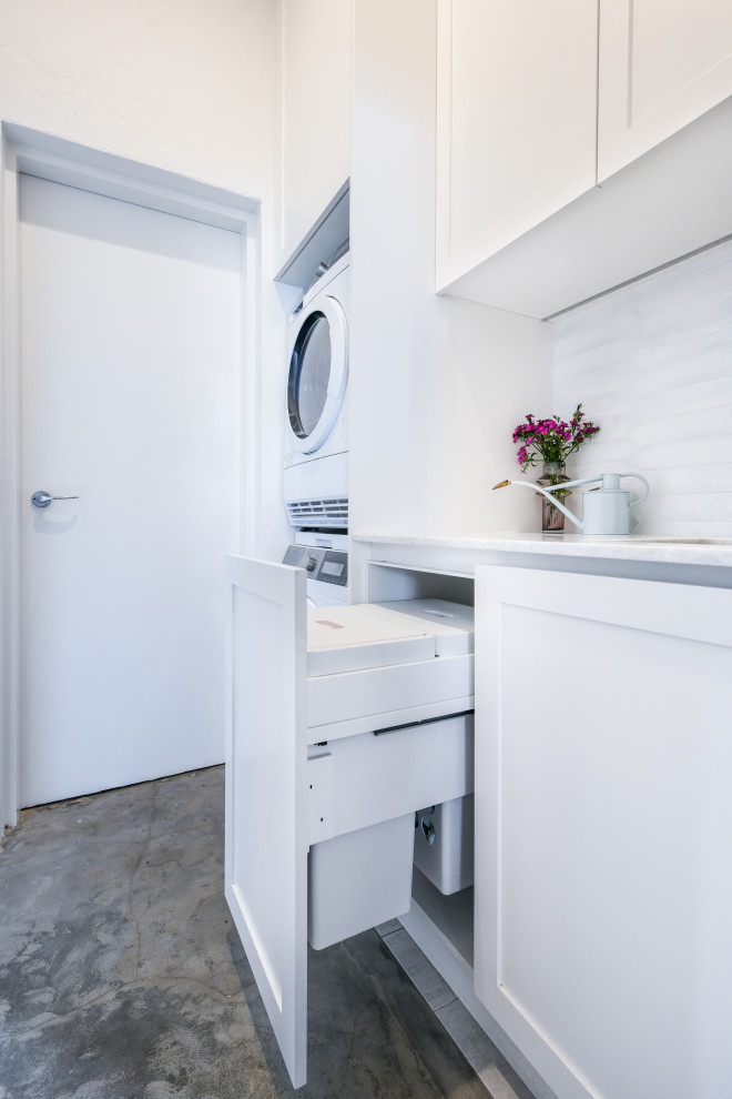Exempel på en liten maritim grå linjär grått tvättstuga enbart för tvätt, med en undermonterad diskho, skåp i shakerstil, vita skåp, bänkskiva i kvartsit, vitt stänkskydd, stänkskydd i keramik, vita väggar och en tvättpelare