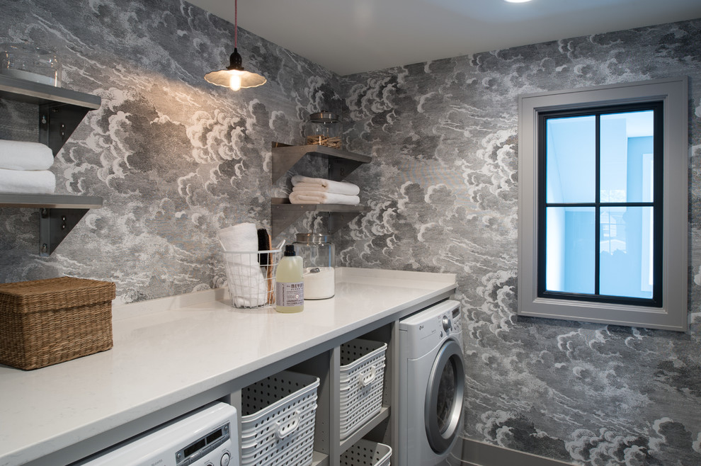 Klassisk inredning av en mellanstor linjär tvättstuga enbart för tvätt, med öppna hyllor, bänkskiva i kvarts, grå väggar och en tvättmaskin och torktumlare bredvid varandra