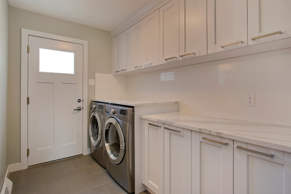 Foto på en mellanstor vintage linjär tvättstuga enbart för tvätt, med skåp i shakerstil, vita skåp, marmorbänkskiva, grå väggar, klinkergolv i porslin och en tvättmaskin och torktumlare bredvid varandra