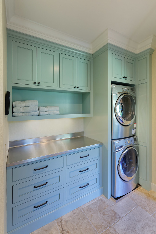 This is an example of a traditional utility room in Cincinnati with shaker cabinets, green cabinets, stainless steel worktops and a stacked washer and dryer.