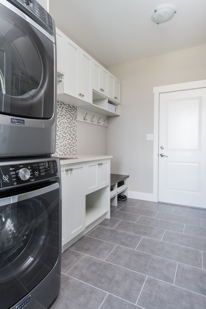 Ejemplo de cuarto de lavado lineal tradicional renovado de tamaño medio con fregadero encastrado, armarios estilo shaker, puertas de armario blancas, encimera de laminado y lavadora y secadora apiladas