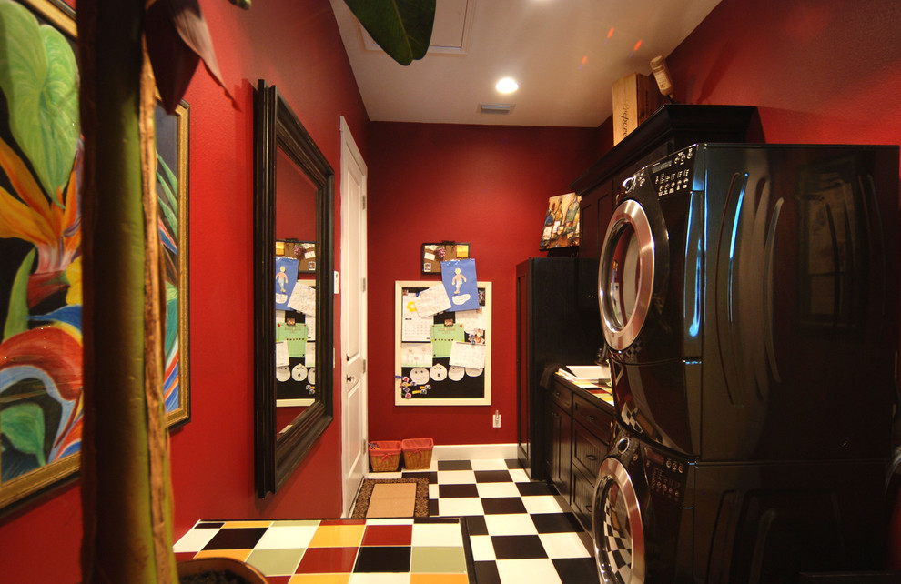タンパにある中くらいなエクレクティックスタイルのおしゃれな洗濯室 (I型、落し込みパネル扉のキャビネット、黒いキャビネット、赤い壁、リノリウムの床、上下配置の洗濯機・乾燥機) の写真