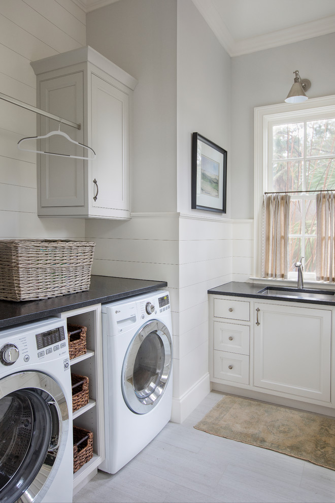 Inspiration for a nautical separated utility room in Charleston with a submerged sink, beaded cabinets, white cabinets, a side by side washer and dryer, grey floors, black worktops and a dado rail.