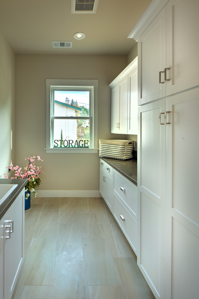 Exemple d'une buanderie parallèle tendance de taille moyenne avec un placard à porte shaker, des portes de placard blanches, un plan de travail en quartz modifié, un mur beige, un sol en carrelage de porcelaine et un sol beige.
