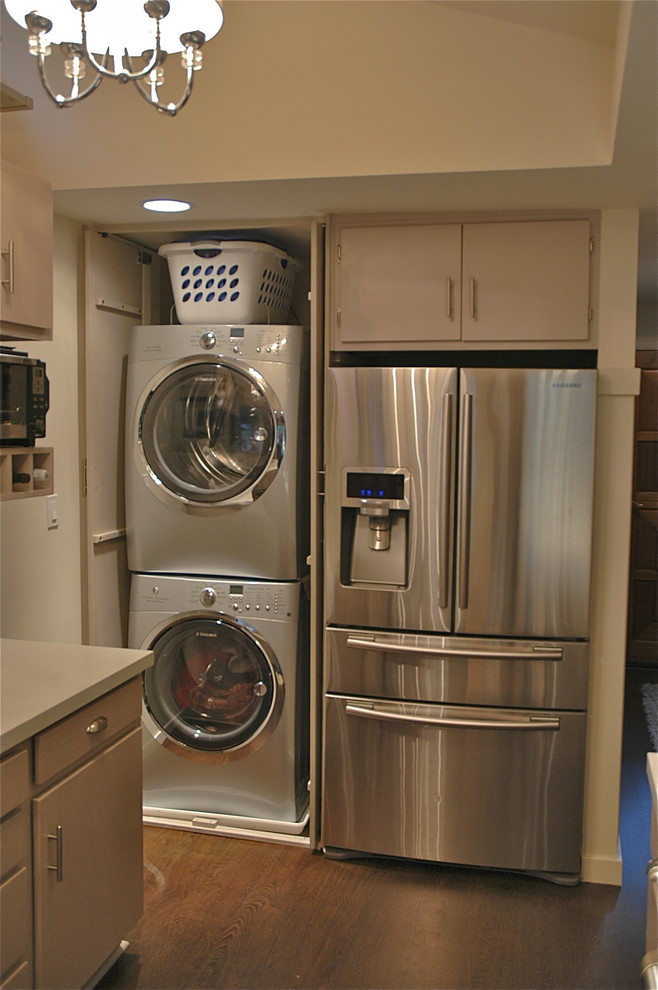 Immagine di un ripostiglio-lavanderia chic di medie dimensioni con pavimento in legno massello medio e lavatrice e asciugatrice nascoste
