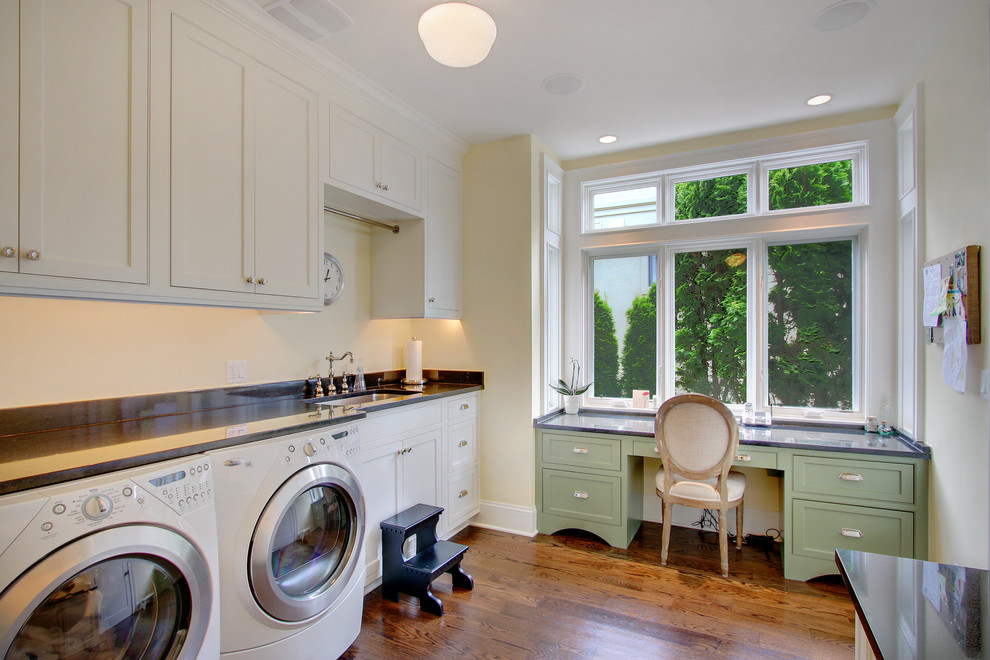 Immagine di una piccola lavanderia multiuso classica con ante bianche, ante con riquadro incassato, pareti bianche, pavimento in legno massello medio, lavatrice e asciugatrice affiancate e lavello sottopiano