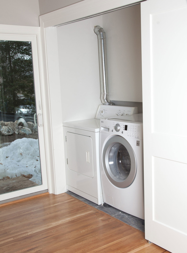 Exempel på en liten klassisk linjär tvättstuga enbart för tvätt, med vita väggar, betonggolv och en tvättmaskin och torktumlare bredvid varandra