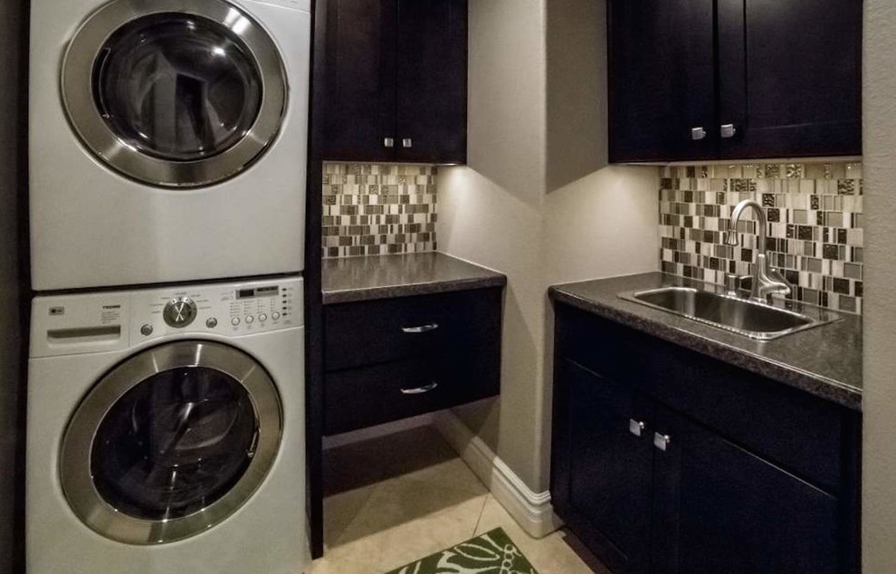 Inspiration for a transitional u-shaped utility room remodel in Phoenix with a drop-in sink, shaker cabinets, dark wood cabinets, granite countertops, beige walls and a stacked washer/dryer