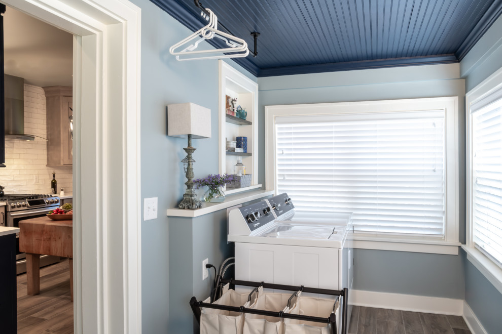 Foto de lavadero multiusos y lineal clásico con paredes azules, suelo de baldosas de porcelana, lavadora y secadora juntas, suelo marrón, madera y panelado