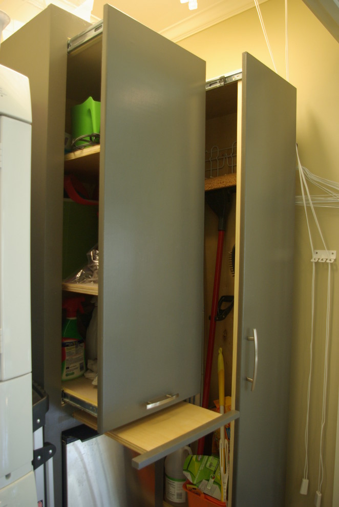 Small classic utility room in Other with flat-panel cabinets, grey cabinets and a stacked washer and dryer.