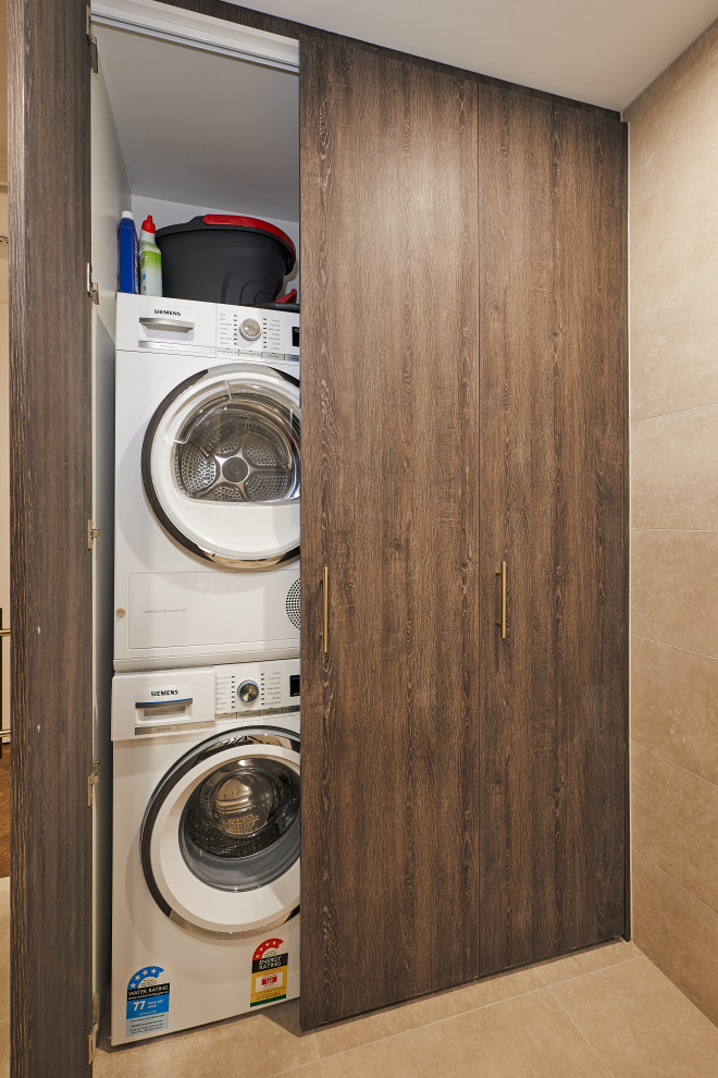 Bild på en funkis tvättstuga, med bruna skåp, klinkergolv i porslin och beiget golv