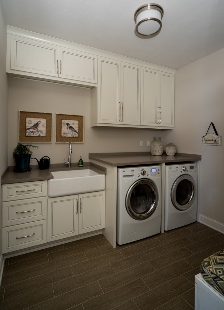This is an example of a medium sized traditional separated utility room in Other with a belfast sink, white cabinets, engineered stone countertops, beige walls, ceramic flooring and a side by side washer and dryer.