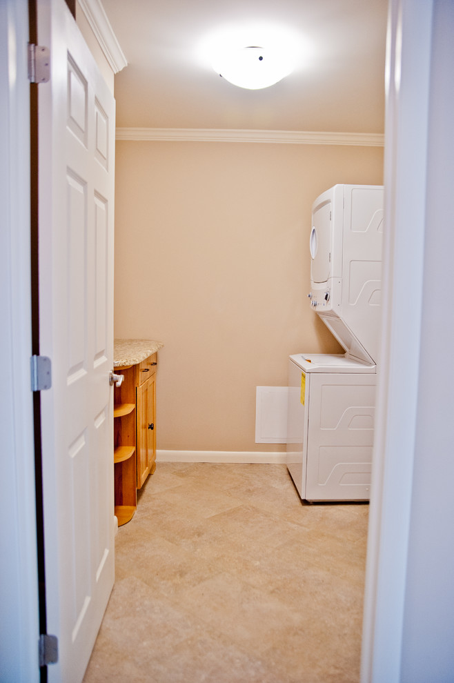 Esempio di una sala lavanderia tradizionale di medie dimensioni con lavatrice e asciugatrice a colonna, ante in stile shaker, top in granito, pareti beige, pavimento in travertino e ante in legno scuro