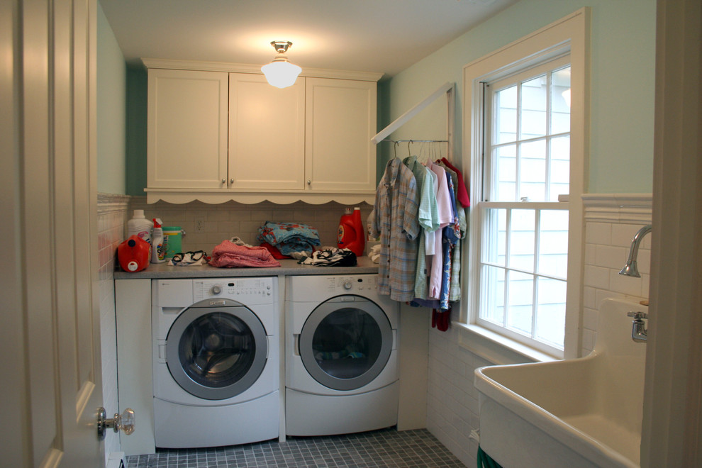 Exempel på en klassisk linjär tvättstuga enbart för tvätt, med en allbänk, vita skåp, blå väggar, en tvättmaskin och torktumlare bredvid varandra, luckor med infälld panel, bänkskiva i koppar och klinkergolv i keramik