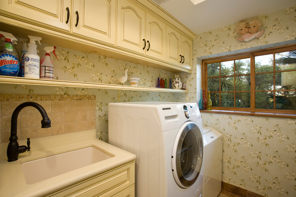 Inredning av en klassisk mellanstor parallell tvättstuga enbart för tvätt, med en undermonterad diskho, luckor med upphöjd panel, gula skåp, bänkskiva i koppar, gröna väggar, klinkergolv i porslin och en tvättmaskin och torktumlare bredvid varandra
