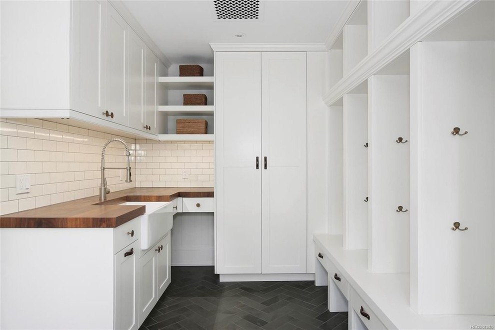 Dedicated laundry room - mid-sized transitional u-shaped porcelain tile and gray floor dedicated laundry room idea in Denver with a farmhouse sink, shaker cabinets, white cabinets, wood countertops, white walls and brown countertops