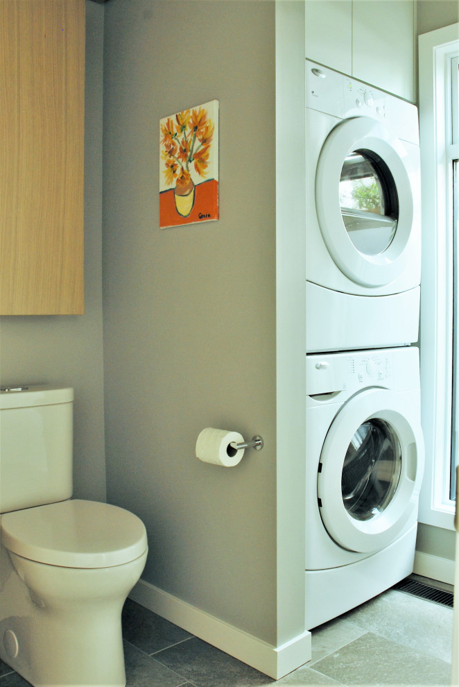 Foto di una piccola lavanderia multiuso contemporanea con ante lisce, ante bianche, pareti blu, pavimento in gres porcellanato, lavatrice e asciugatrice a colonna e pavimento grigio