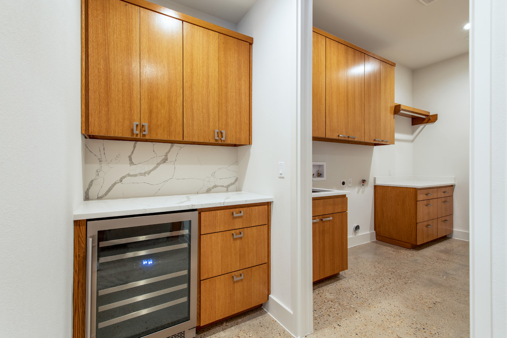 This is an example of a large retro single-wall separated utility room in Austin with a submerged sink, flat-panel cabinets, medium wood cabinets, quartz worktops, white walls, concrete flooring, beige floors and white worktops.