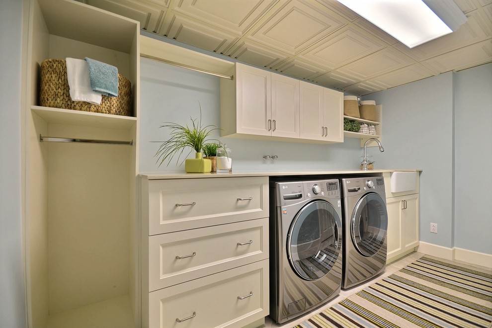 Inspiration for a large timeless single-wall porcelain tile and beige floor dedicated laundry room remodel in Montreal with beige cabinets, a farmhouse sink, blue walls, shaker cabinets, quartz countertops, a side-by-side washer/dryer and beige countertops