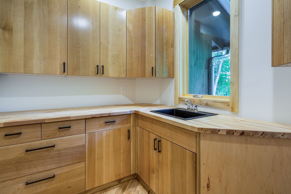 Mid-sized trendy u-shaped light wood floor utility room photo in Other with a drop-in sink, flat-panel cabinets, light wood cabinets, wood countertops, white walls and a side-by-side washer/dryer