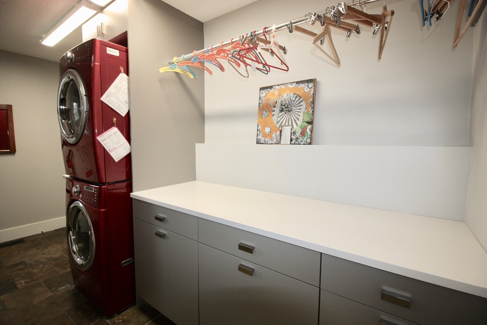 Imagen de lavadero tradicional renovado de tamaño medio con encimera de acrílico, paredes grises, lavadora y secadora juntas y encimeras blancas