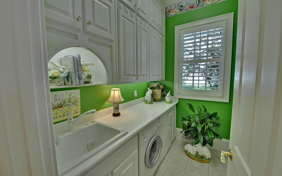 Diseño de lavadero clásico con paredes verdes, suelo gris y encimeras blancas