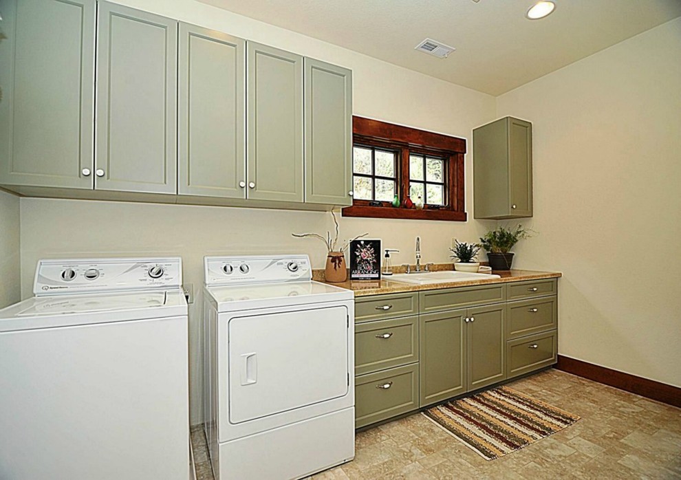 Laundry room - contemporary single-wall vinyl floor laundry room idea in Seattle with a drop-in sink, flat-panel cabinets, green cabinets, solid surface countertops and a side-by-side washer/dryer