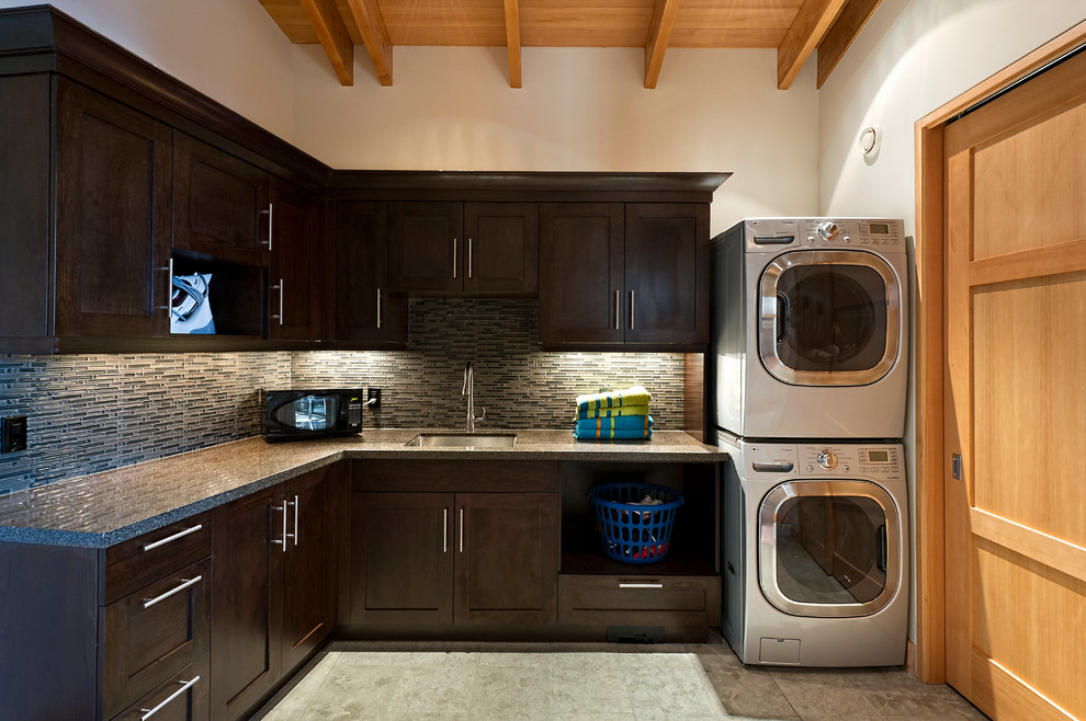 Klassischer Hauswirtschaftsraum mit dunklen Holzschränken und Waschmaschine und Trockner gestapelt in Calgary