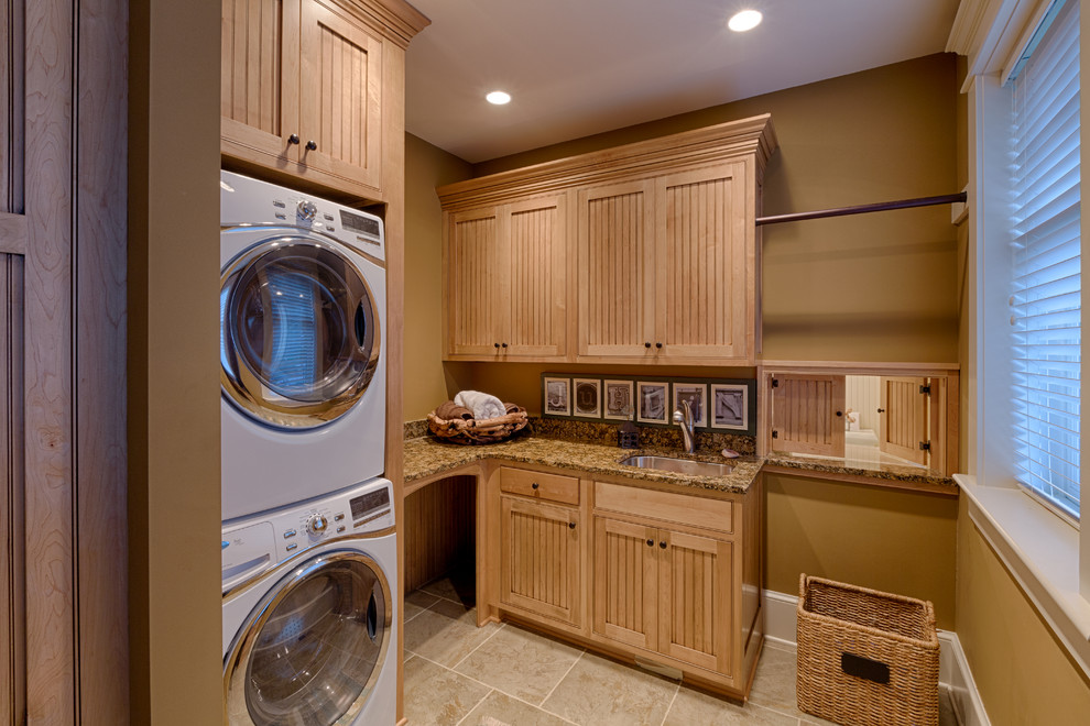 Klassisk inredning av en mellanstor l-formad tvättstuga enbart för tvätt, med en undermonterad diskho, skåp i ljust trä, beige väggar, en tvättpelare, beiget golv och luckor med infälld panel