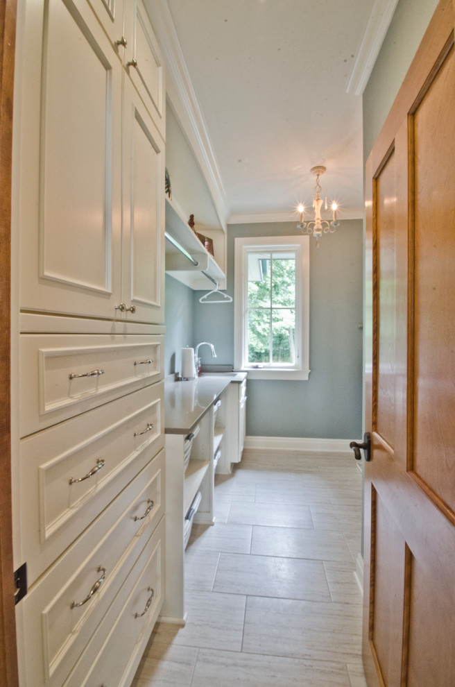 Modelo de lavadero tradicional con armarios con paneles empotrados, puertas de armario blancas, paredes grises y suelo de baldosas de cerámica