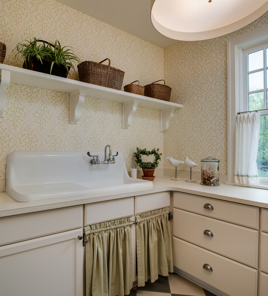 Immagine di una sala lavanderia chic con lavello da incasso, ante con riquadro incassato, ante beige, pareti beige, pavimento grigio e top beige
