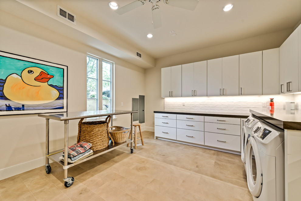 This is an example of an expansive contemporary l-shaped separated utility room in Dallas with a submerged sink, flat-panel cabinets, white cabinets, engineered stone countertops, grey walls, ceramic flooring, a side by side washer and dryer and beige floors.