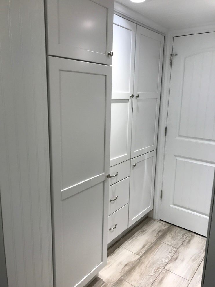 Dedicated laundry room - small transitional galley porcelain tile and gray floor dedicated laundry room idea in Milwaukee with shaker cabinets, white cabinets, quartz countertops, white walls and a stacked washer/dryer