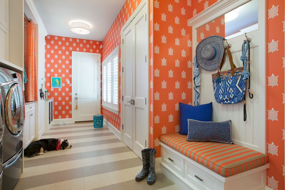 Immagine di una lavanderia multiuso classica con ante con riquadro incassato, ante bianche, pareti arancioni e lavatrice e asciugatrice affiancate