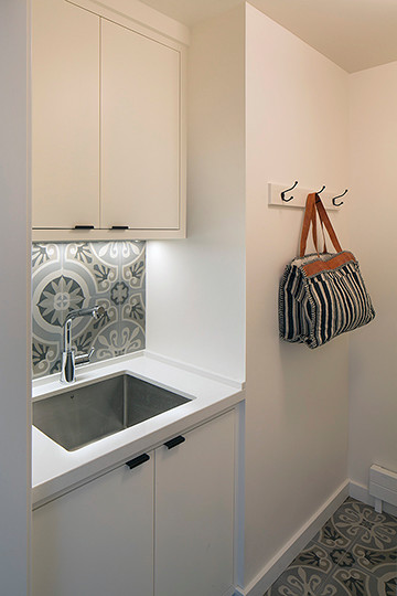 Foto di una lavanderia multiuso rustica di medie dimensioni con lavello da incasso, ante lisce, ante bianche, pareti bianche, pavimento in cemento e lavatrice e asciugatrice affiancate