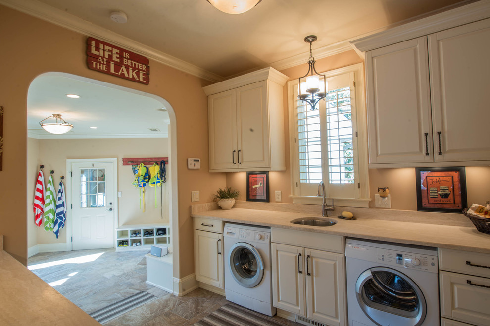 This is an example of a medium sized classic galley utility room in Atlanta with white cabinets, a side by side washer and dryer, a submerged sink, raised-panel cabinets, limestone worktops, beige walls and porcelain flooring.