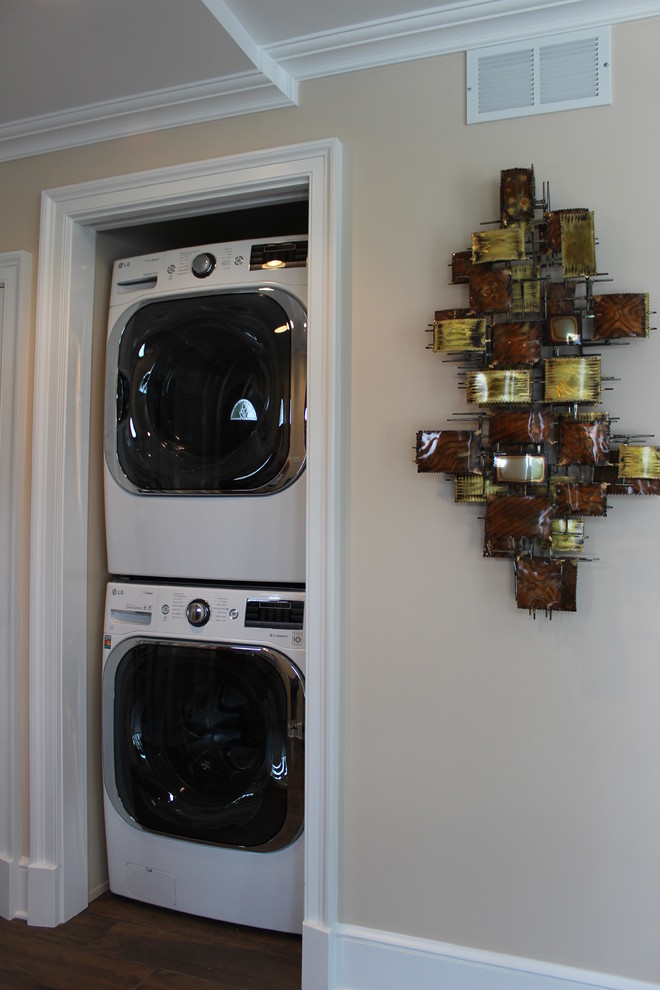 Esempio di un piccolo ripostiglio-lavanderia classico con pareti beige, pavimento in vinile e lavatrice e asciugatrice a colonna